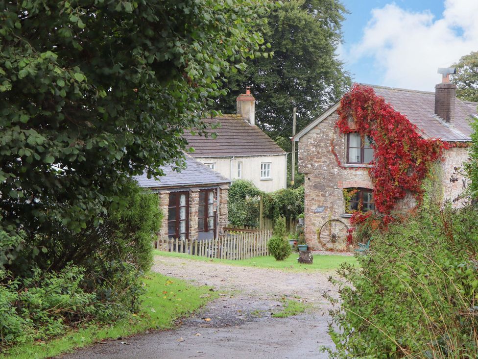 A house and cabin surrounded by greenery at The Milking Shippon at Thorne near Great Torrington