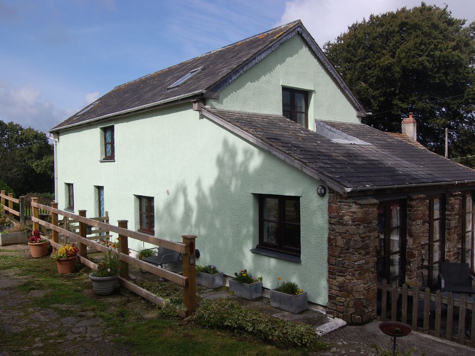 A house with a stone wall and windows at The Milking Shippon at Thorne Langtree near Great Torrington