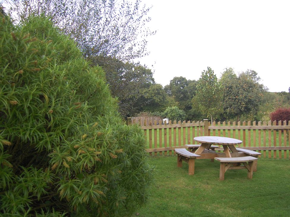 A garden with a picnic table and bushes at The Milking Shippon at Thorne near Great Torrington