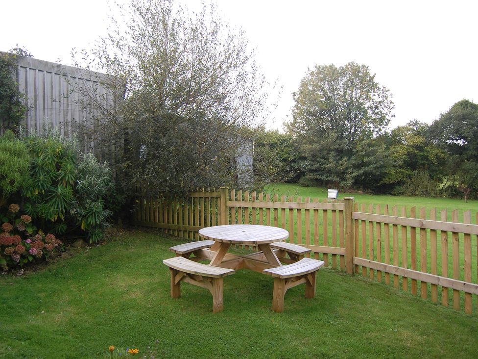 A garden with a wooden table and benches at The Milking Shippon at Thorne in Langtree near Great Torrington
