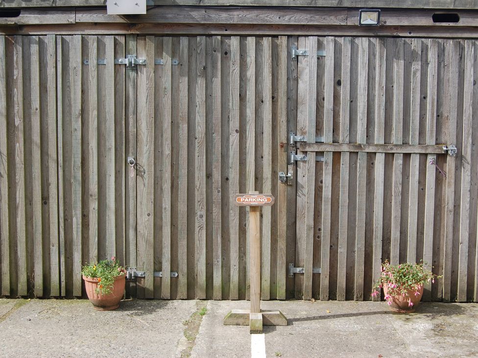 An outdoor area with a wooden door and parking sign at The Milking Shippon at Thorne Langtree near Great Torrington