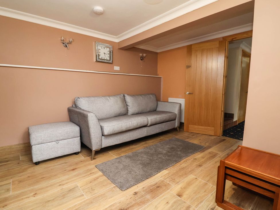 A living room with a sofa and footstool at Ty Cerrig apartment