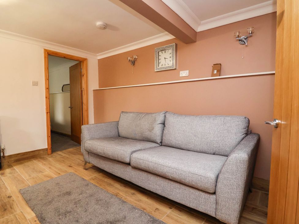 A living room with a sofa and clock at Ty Cerrig apartment