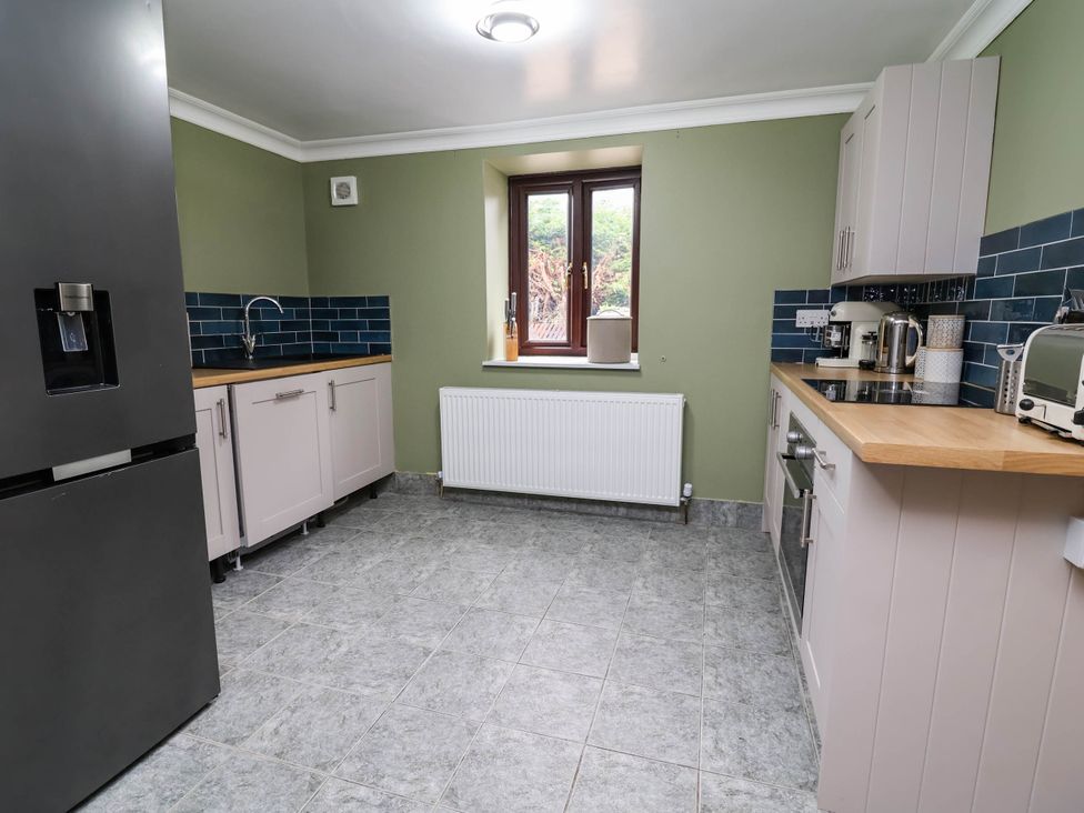 A kitchen with a refrigerator and sink at Ty Cerrig apartment