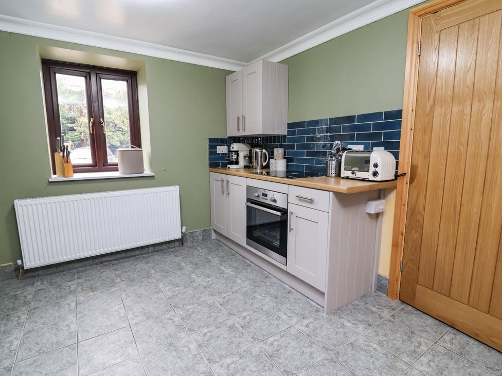 A kitchen with cabinets and appliances at Ty Cerrig apartment