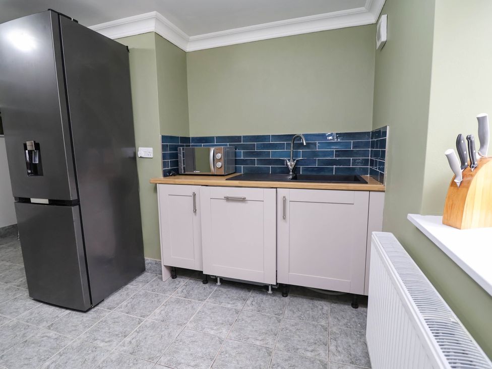 A kitchen with counter, microwave, sink, and refrigerator at Ty Cerrig apartment