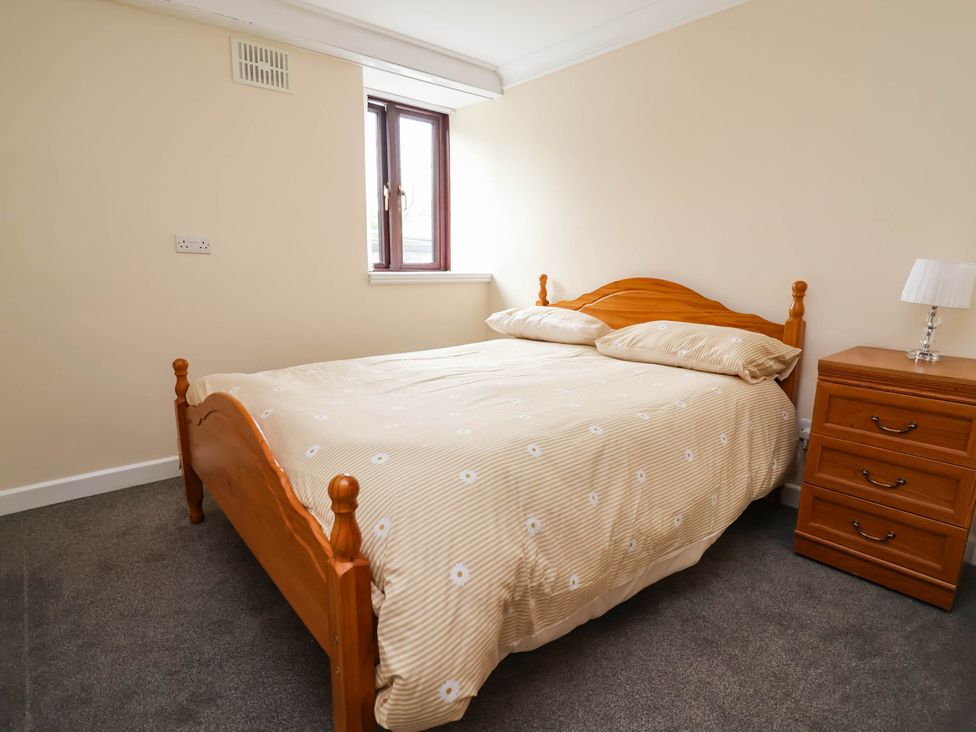 A bedroom with a bed and nightstand at Ty Cerrig apartment 
