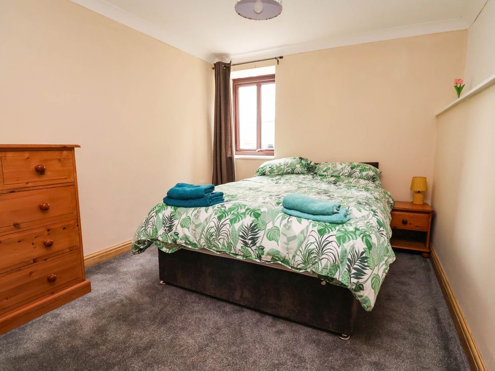 A bedroom with a bed and dresser at Ty Cerrig apartment