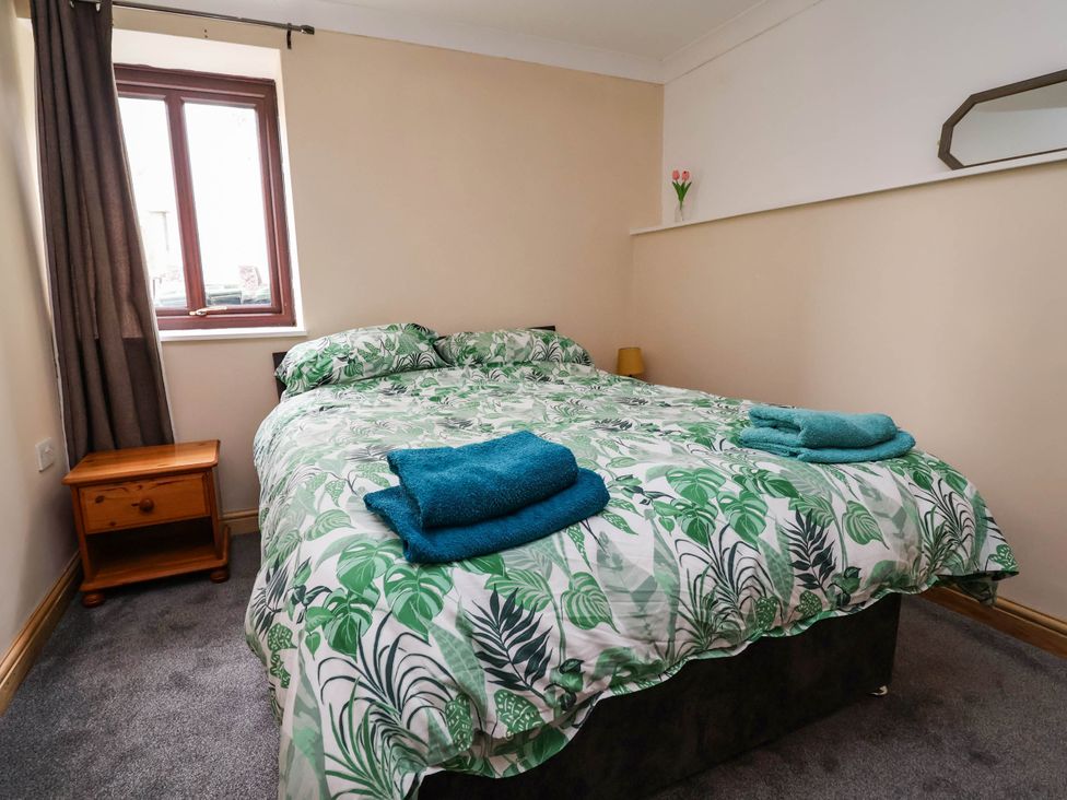 A bedroom with a double bed and a nightstand at Ty Cerrig apartment