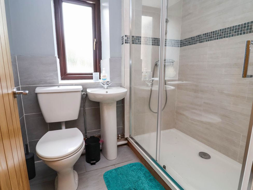 A bathroom with a toilet, sink, and shower at Ty Cerrig apartment 