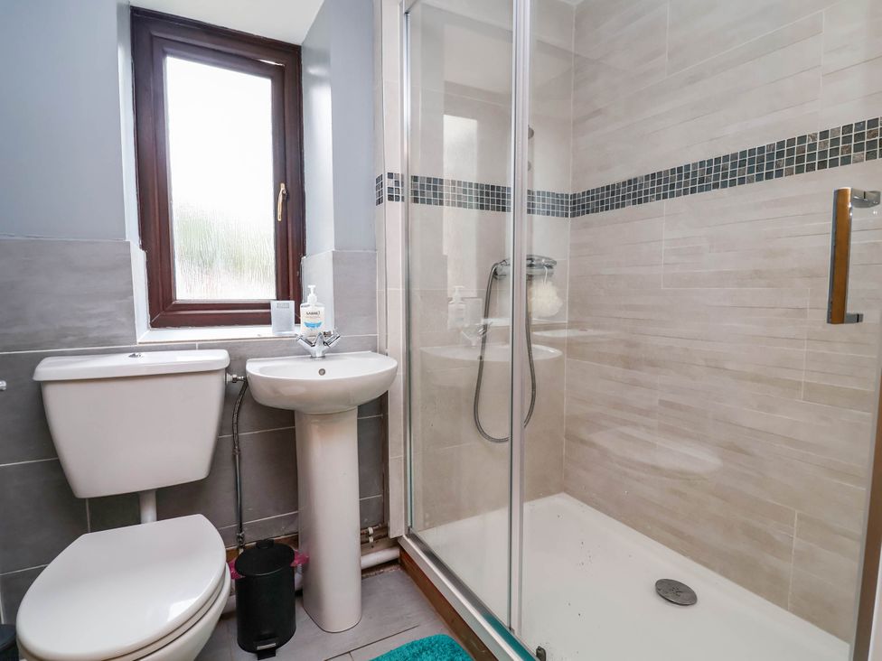 A bathroom with a sink, toilet, and shower at Ty Cerrig apartment