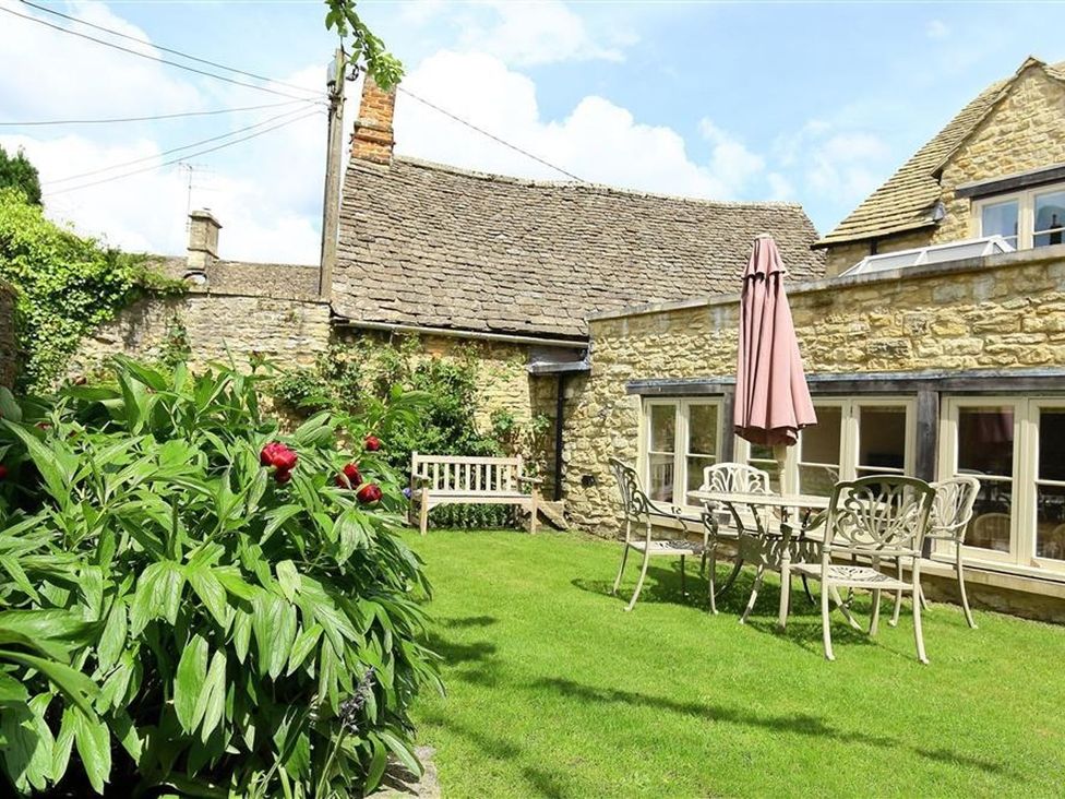 A garden with a bench and table at The Coach House in Burford
