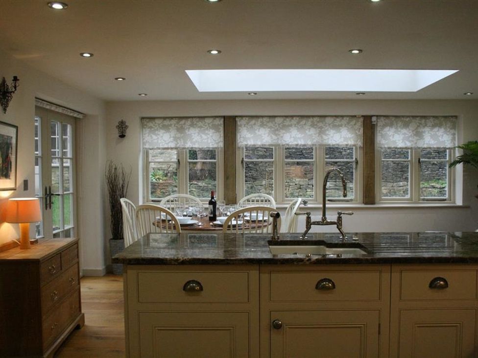 A kitchen with a table and chairs near windows at The Coach House Burford