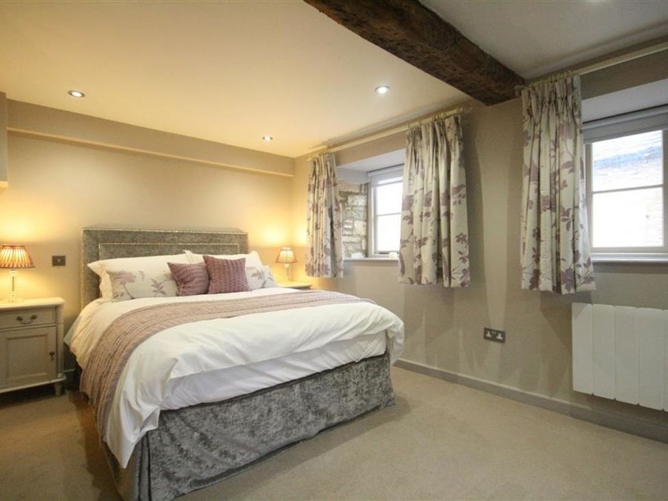 A bedroom with a bed and nightstand at The Coach House in Burford