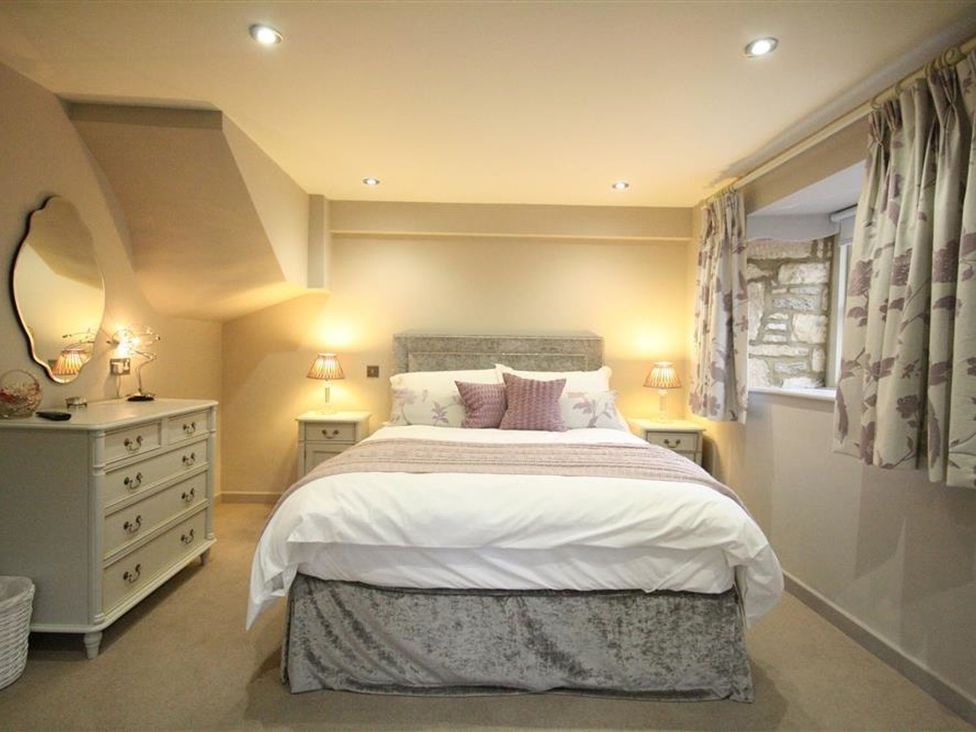 A bedroom with a bed and dresser at The Coach House in Burford