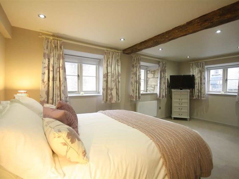 A bedroom with a bed and a TV at The Coach House in Burford