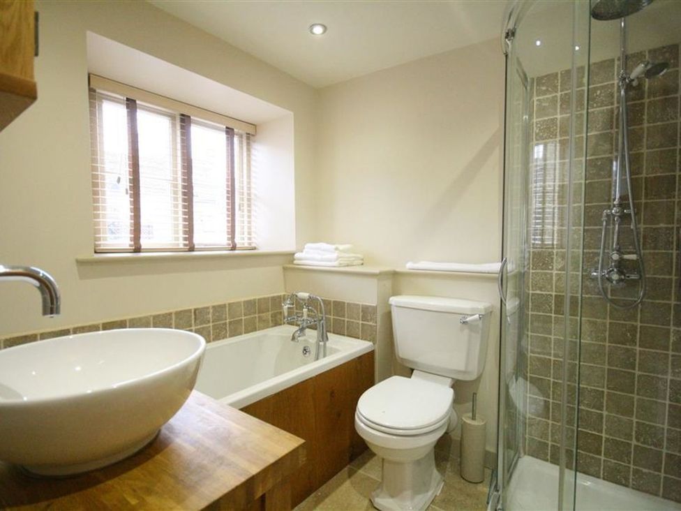 A bathroom with a bathtub, toilet, and shower at The Coach House in Burford