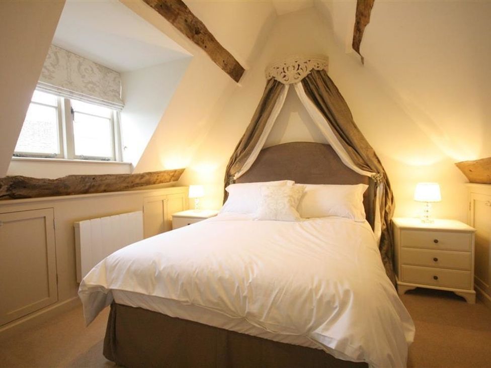 A bedroom with a bed and nightstand at The Coach House in Burford