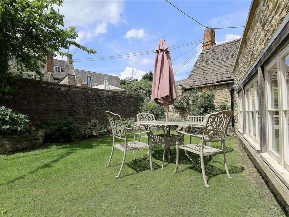 A garden with a table and chairs set and an umbrella at The Coach House in Burford