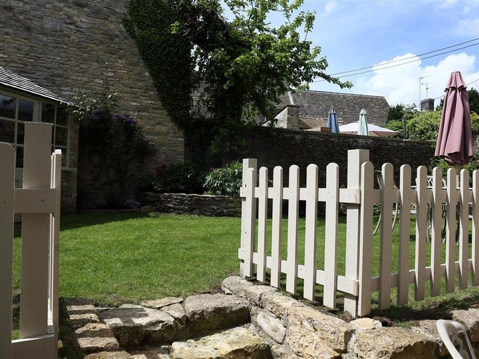 A garden with a fence and stone wall at The Coach House in Burford