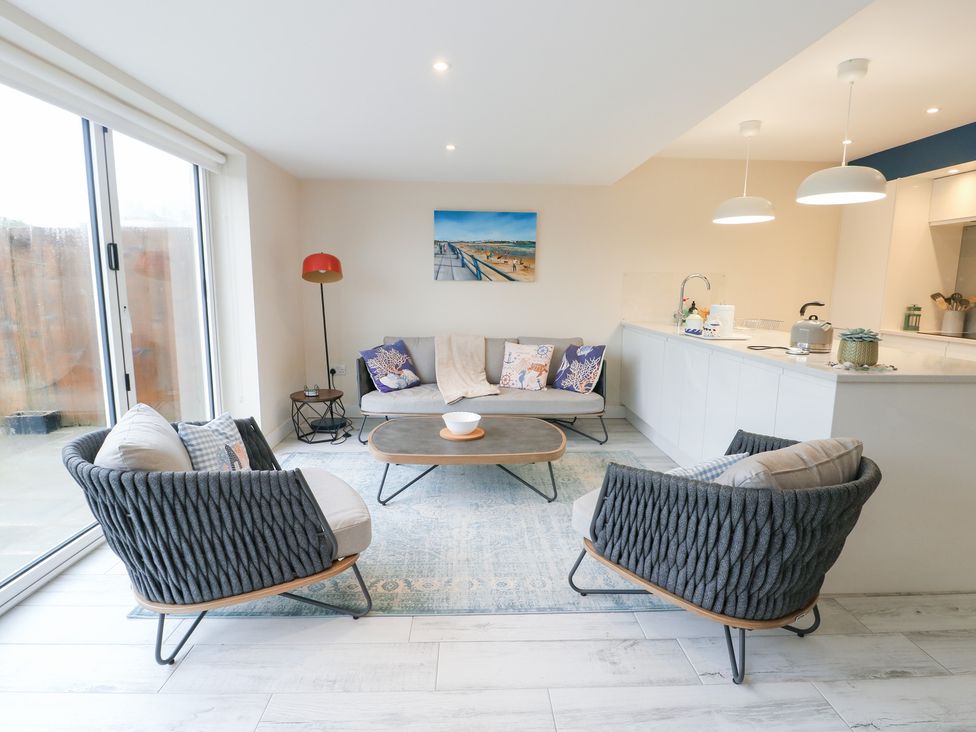 A living room with seating area and kitchen cabinetry at 2 Lon Y Dryw Trearddur Bay