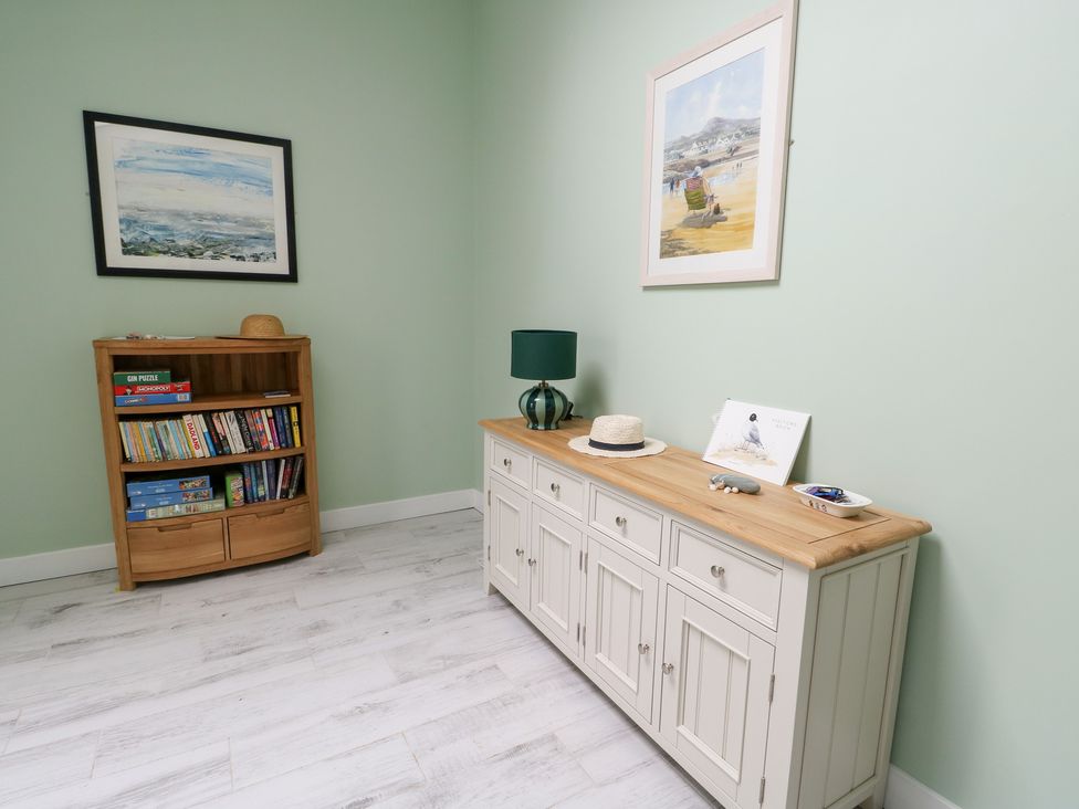 A living room with a bookshelf and console table at 2 Lon Y Dryw Trearddur Bay