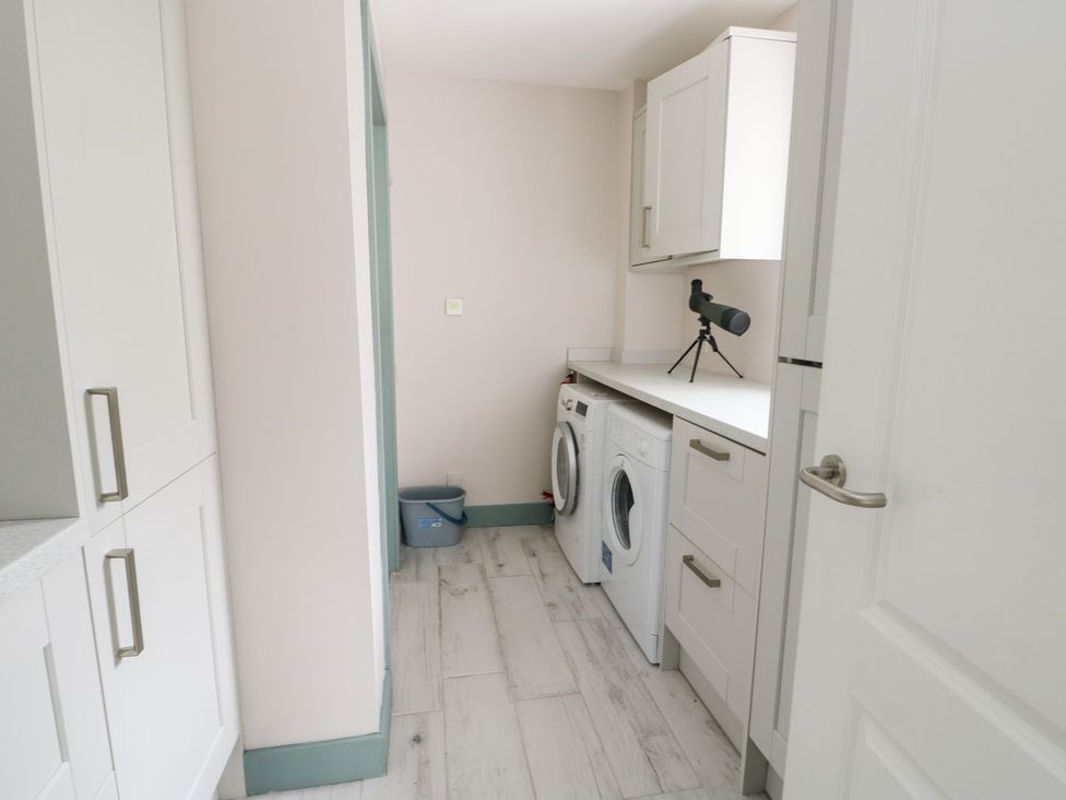A laundry room with a washing machine and dryer at 2 Lon Y Dryw Trearddur Bay
