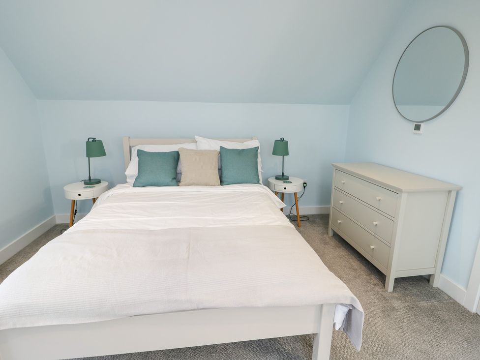A bedroom with a bed, nightstands, dresser, and mirror at 2 Lon Y Dryw in Trearddur Bay