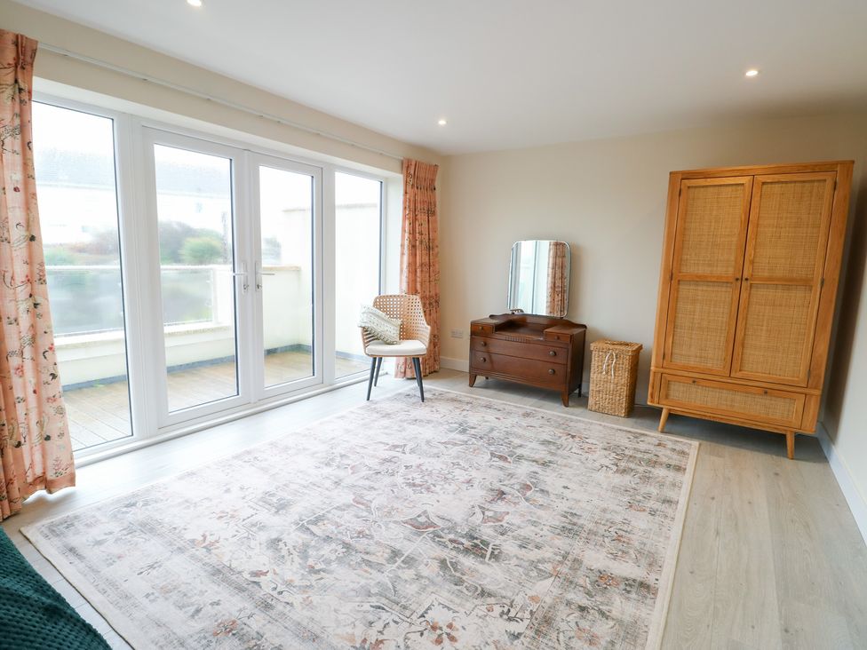 A living room with sliding doors and furniture at 2 Lon Y Dryw in Trearddur Bay