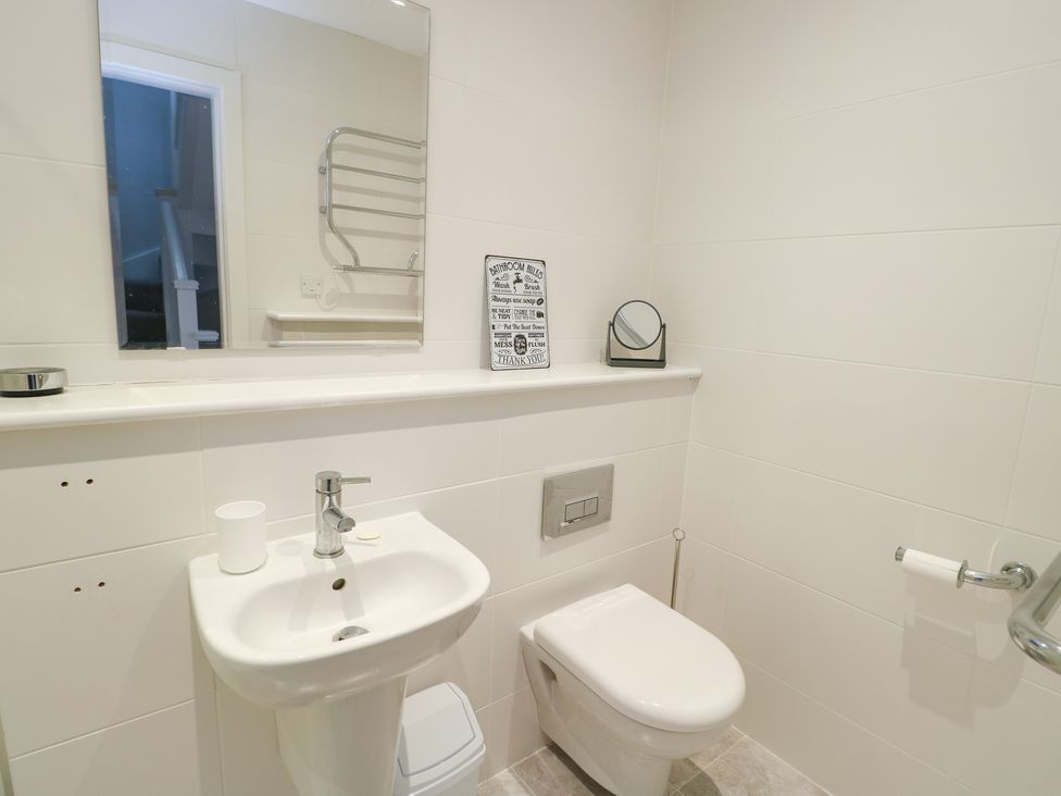 A bathroom with a sink, toilet, and mirror at 2 Lon Y Dryw in Trearddur Bay