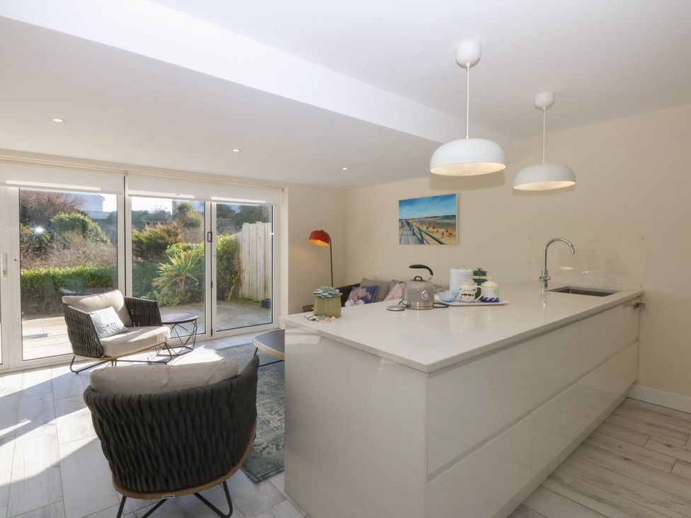 A kitchen with a dining area and sliding doors at 2 Lon Y Dryw in Trearddur Bay