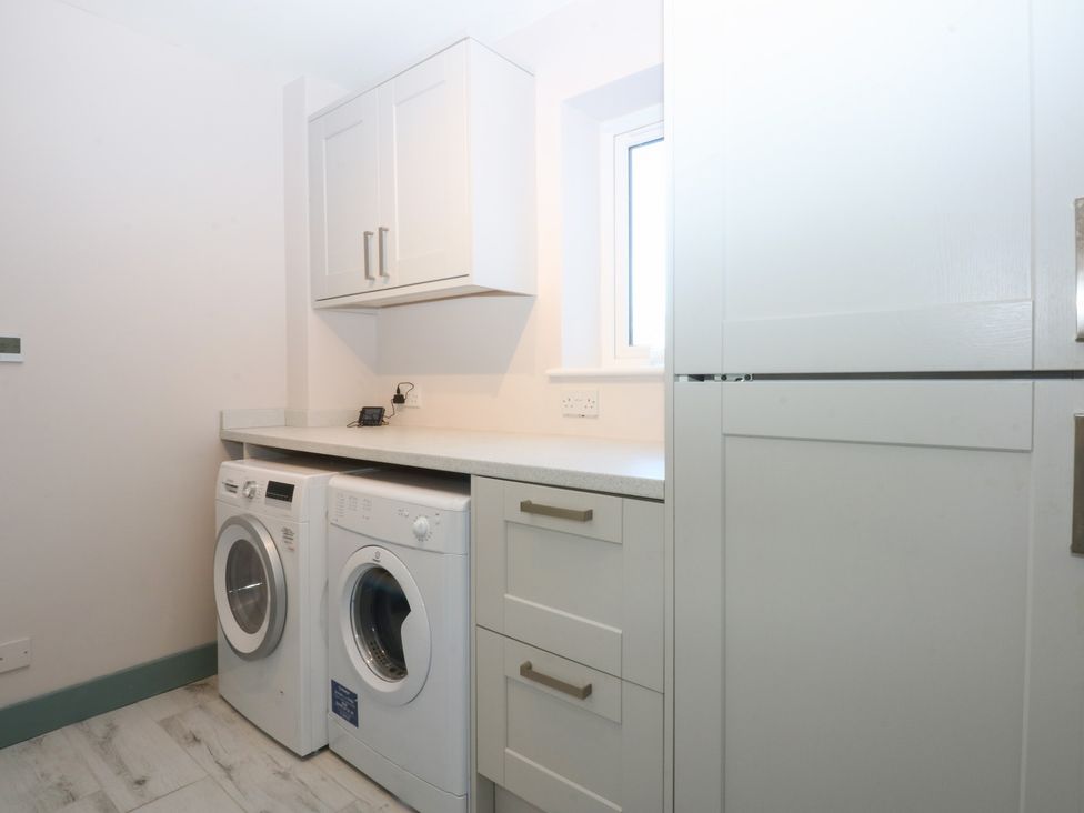 A laundry room with a washing machine and dryer at 2 Lon Y Dryw in Trearddur Bay
