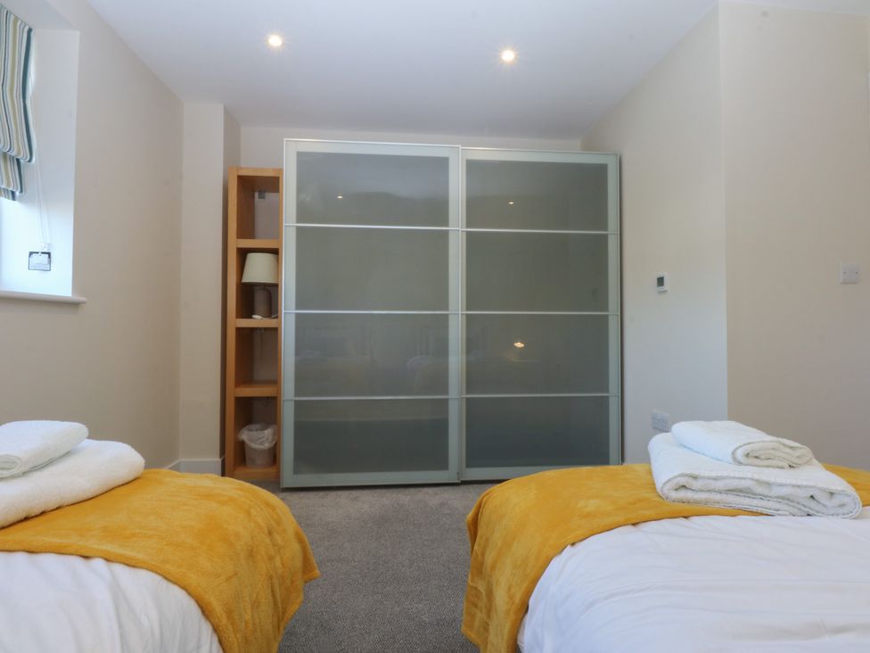 A bedroom with two beds and a wardrobe at 2 Lon Y Dryw in Trearddur Bay