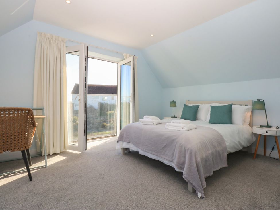 A bedroom with a bed and a table at 2 Lon Y Dryw in Trearddur Bay