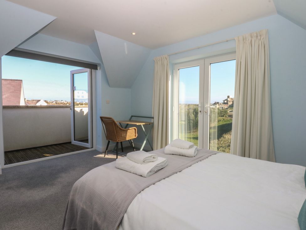A bedroom with a bed, chair, and table at 2 Lon Y Dryw in Trearddur Bay