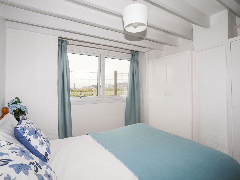 A bedroom with a bed and a window at Rhiw - 1 Ty'n Don Abersoch