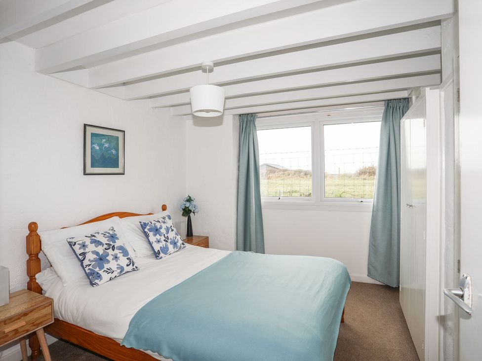 A bedroom with a bed and windows at Rhiw - 1 Ty'n Don Abersoch