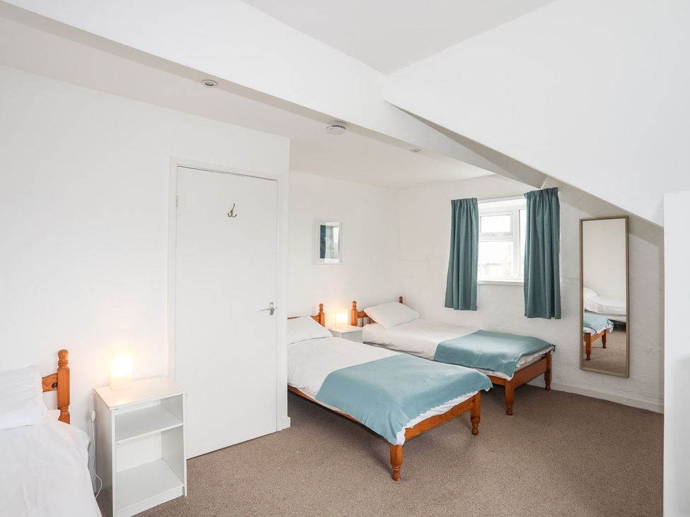 A bedroom with two beds and a mirror at Rhiw - 1 Ty'n Don in Abersoch