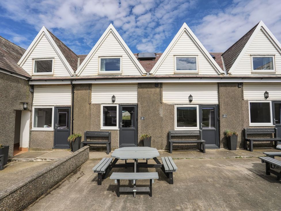 An outdoor area with a table and benches at Rhiw - 1 Ty'n Don in Abersoch