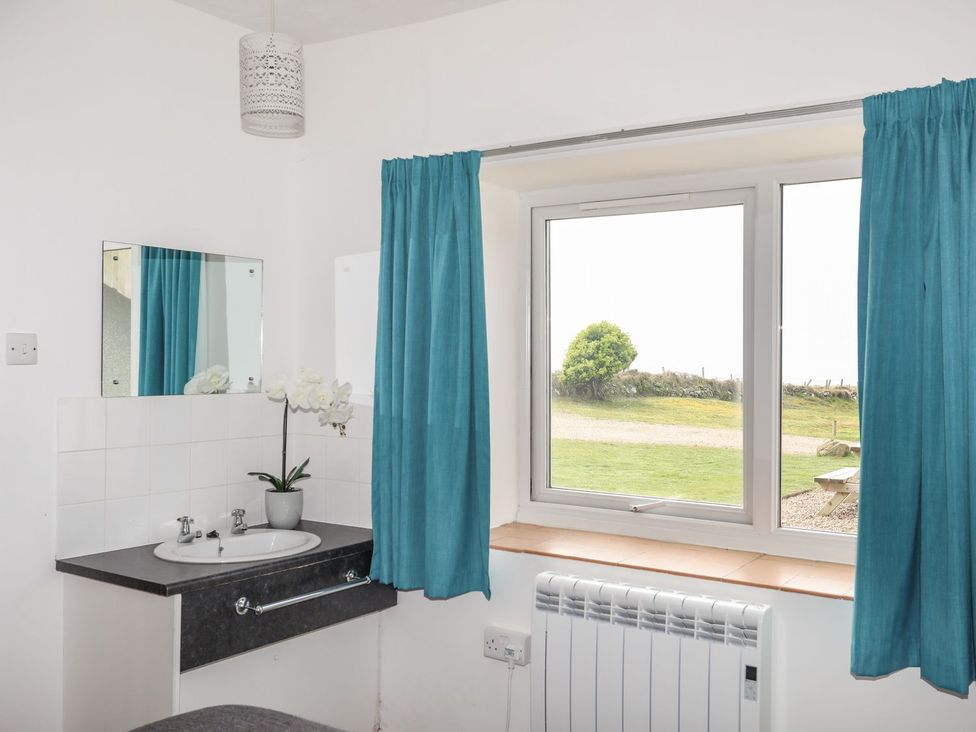 A bathroom with a sink and mirror at Oer - 8 Ty'n Don Llanengan near Abersoch