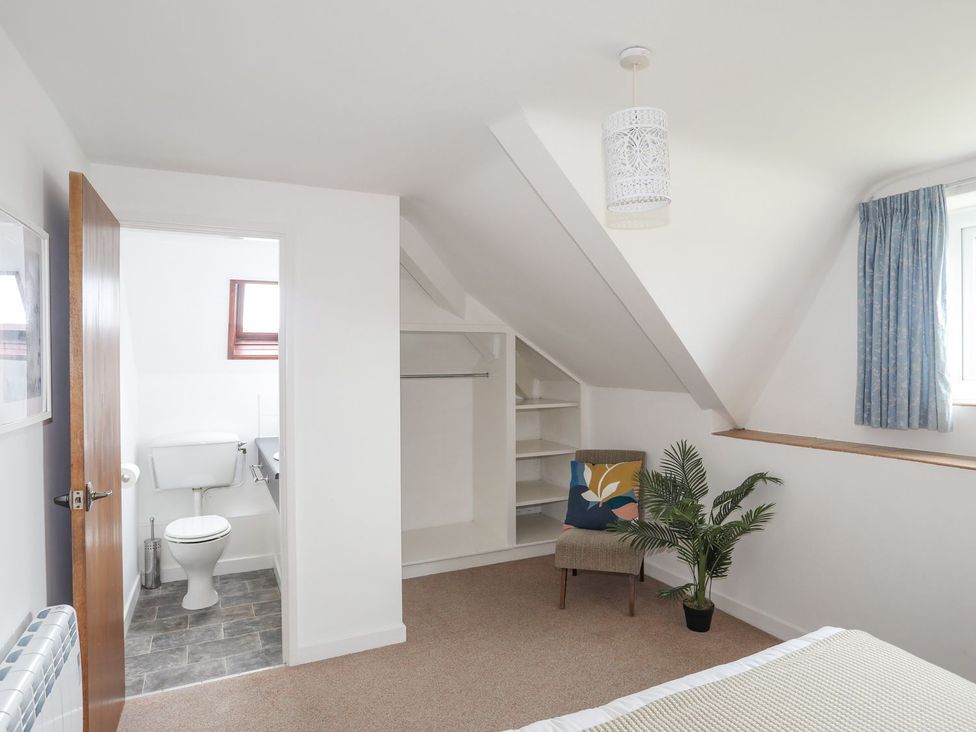 A bedroom with a chair and a view of a bathroom at Ysgo - 6 Ty'n Don Abersoch