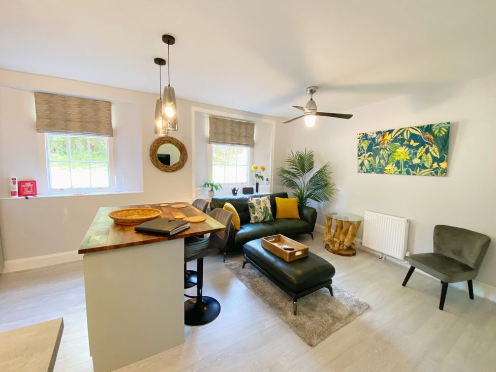 A living room with a sofa, coffee table, and windows at Meadfoot Bay Apartment at Hesketh Crescent Torquay