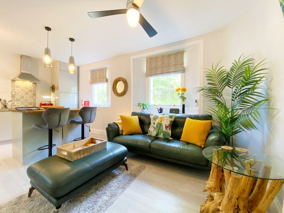 A living room with a sofa and kitchen area at Meadfoot Bay Apartment at Hesketh Crescent Torquay