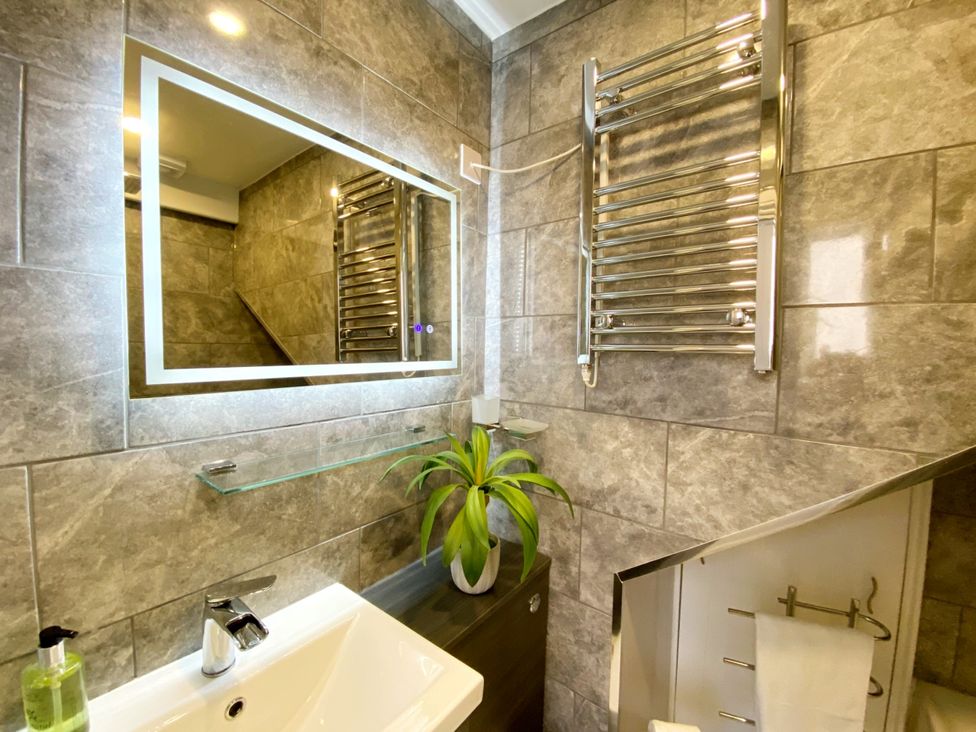 A bathroom with a mirror, sink, and towel radiator at Meadfoot Bay Apartment at Hesketh Crescent in Torquay