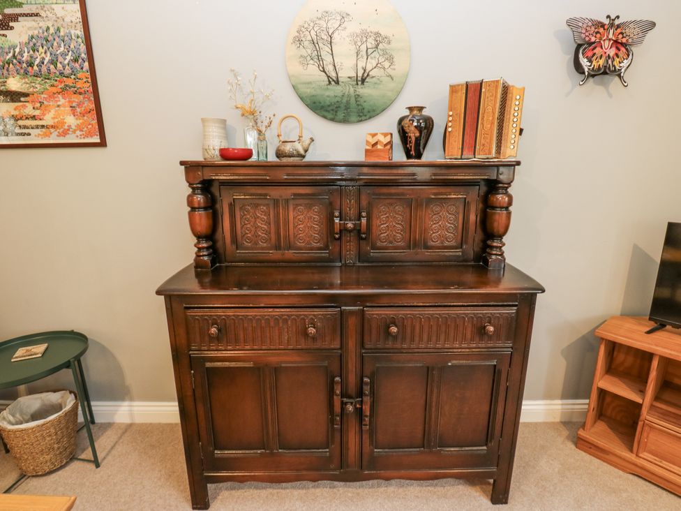 A cabinet with decorative items and a wall art in a living room at The Treetop