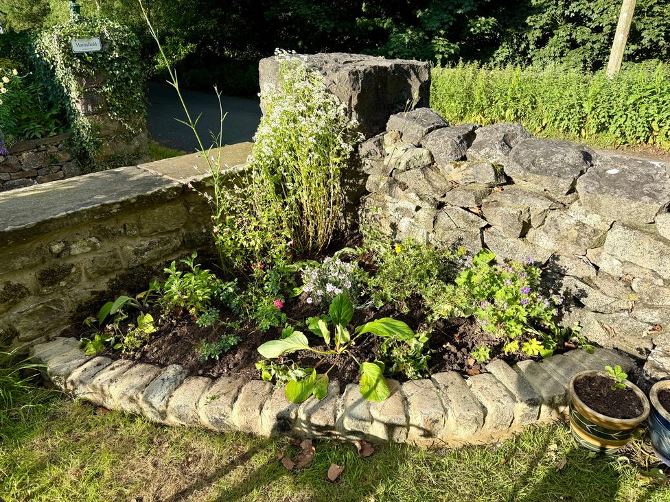 A garden with a flowerbed and stone wall at The Treetop in Giggleswick near Settle