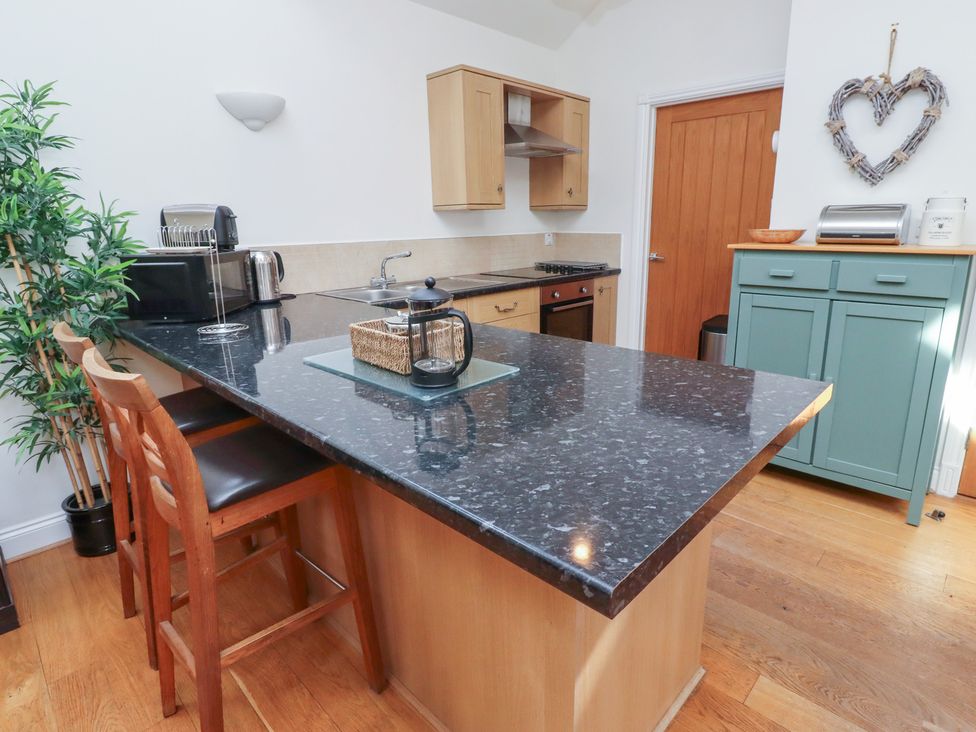 A kitchen with counter, stools, and appliances at Hideaway Cottage No 1 Seahouses