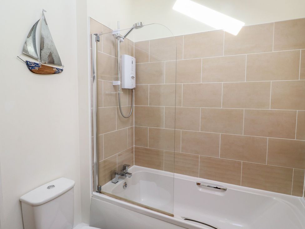 A bathroom with a bathtub and shower at Hideaway Cottage No 1 Seahouses