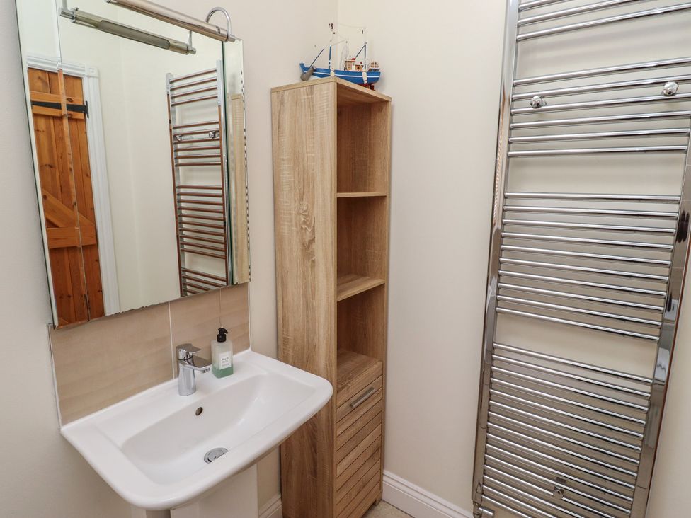 A bathroom with a sink and a mirror at Hideaway Cottage No 1 Seahouses