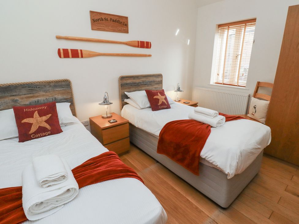A bedroom with two beds and a nightstand at Hideaway Cottage No 1 Seahouses
